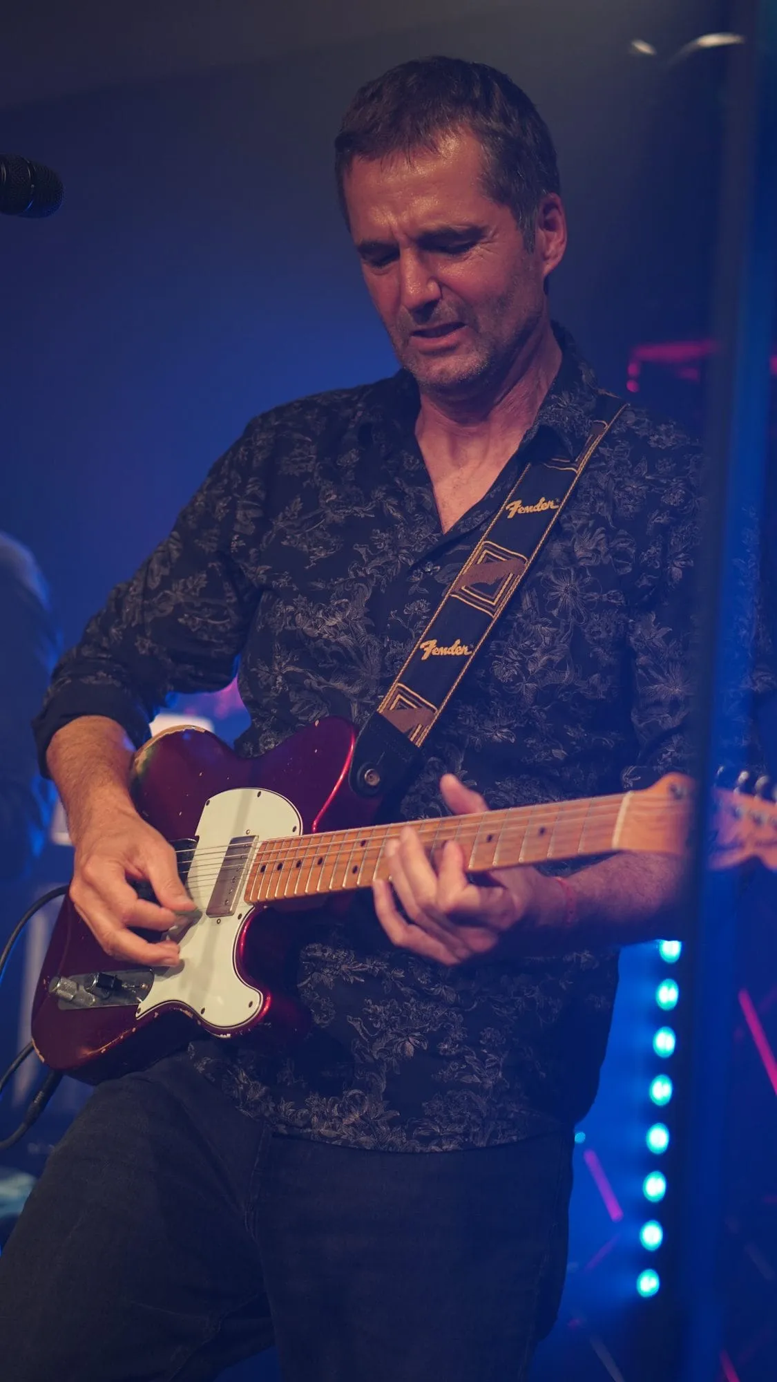 Jochen Probst spielt Gitarre, konzentriert, blaues Bühnenlicht