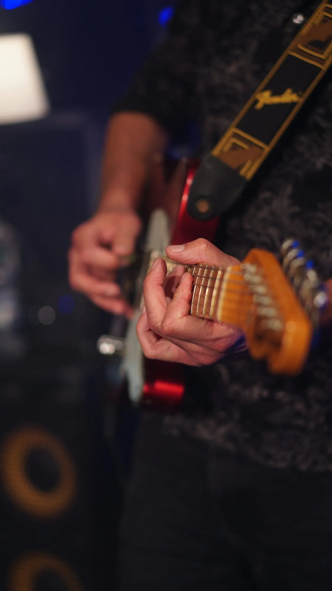 Nahaufnahme von Jochens Händen auf dem Griffbrett einer roten Fender-Gitarre
